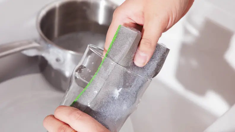Person using Skura Sponge to clean glass in sink.