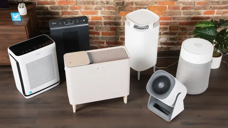 A selection of multiple air purifiers laid out on a row on the floor.