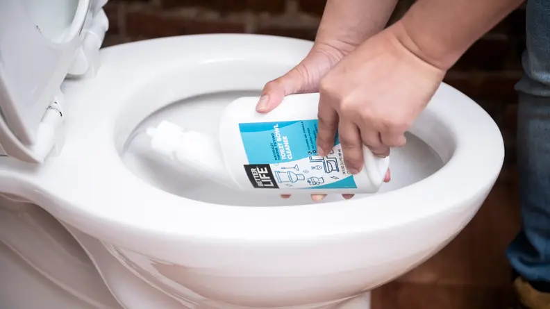 A person squirts liquid cleaner into the bowl of a toilet