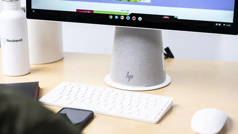 A wireless keyboard and mouse sit in front of the computer base