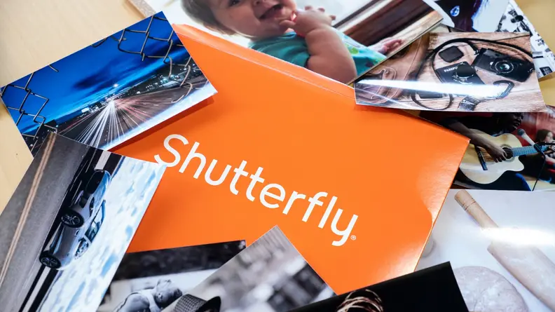 Shutterfly logo on an orange envelope with several photos around it.