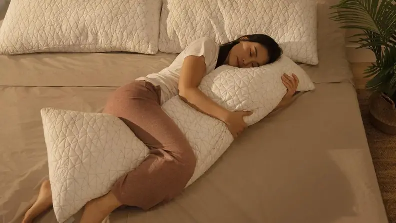 A person cuddled up with a large body pillow.