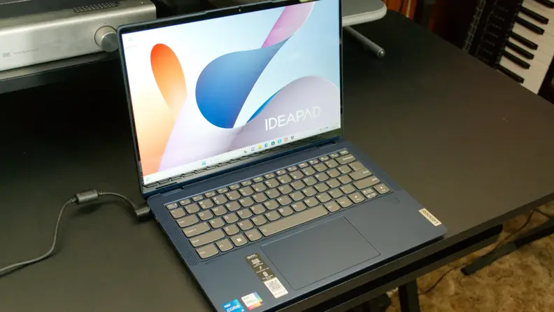 Blue Lenovo IdeaPad Flex 5i 14 Laptop with display turned on while on top of black desk surface.