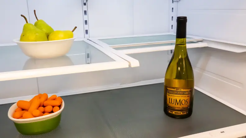 A tall bottle of wine is accommodated by the Hisense HRF266N6CSE French-door refrigerator's flex shelf being partially slid under itself. This results in a shelf that's half the depth of a typical shelf, allowing items stored below and in front of the shelf to have much more space.
