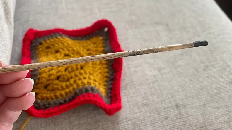 Wooden crochet hook against a couch