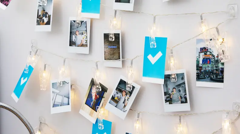 Polaroid photos clipped to string lights in a dorm room.