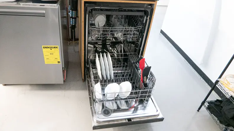 A close-up of the dishwasher installed in our testing labs, open with its racks pulled out, full of clean dishes.
