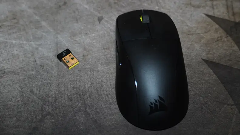 The Corsair M75 Air next to a USB plug, on a grey background.