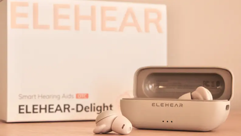 ELEHEAR Delight OTC Hearing Aids with one bud inside the case and one out, in front of its box.