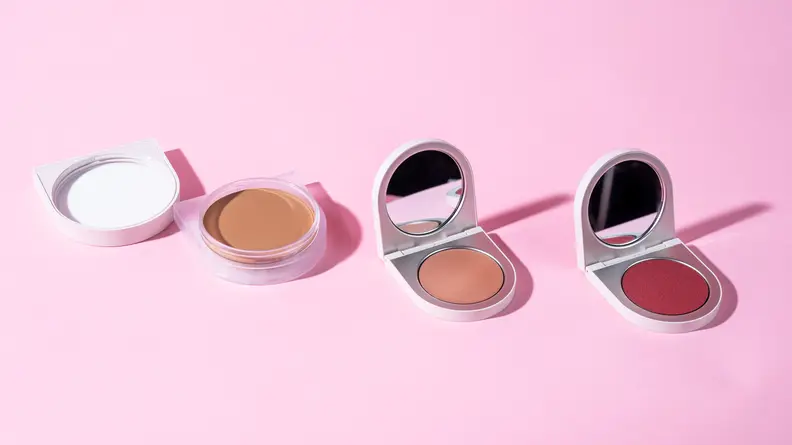 Compacts of Rose Inc. cream foundation, highlighter and blush.