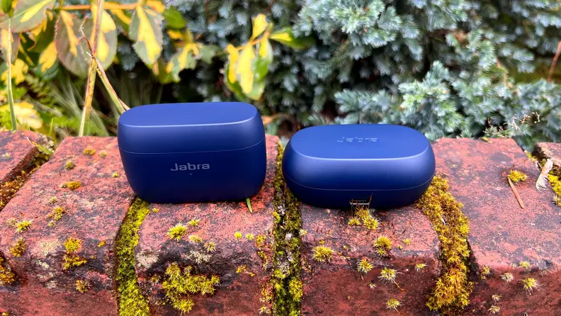 The Elite 4 Active and Elite 7 Active earbuds sit in navy cases closed on a mossy brick ledge.