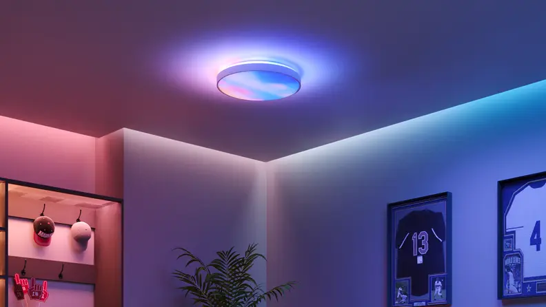 A round smart ceiling light casts colorful blue and pink illumination across the ceiling and walls of a modern room.