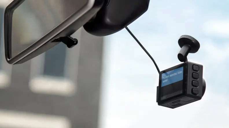 A dash cam affixed to a car windshield.
