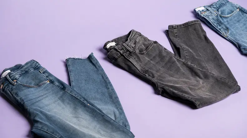 Three pairs of jeans on a purple background