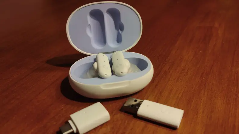 Close-up of the earbuds inside their case with two USB dongles.