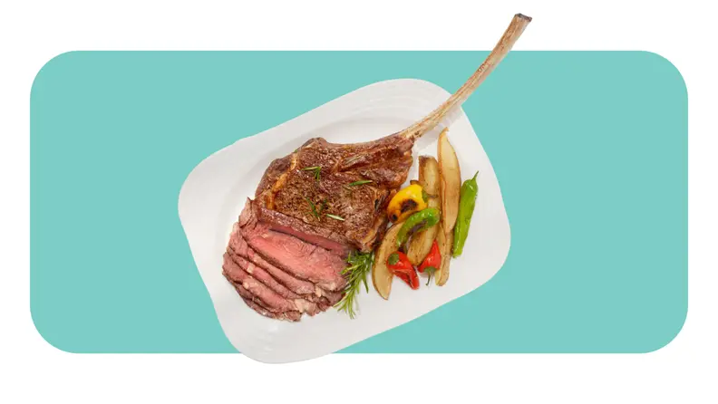 Bone-in steak served on a plate with veggies.