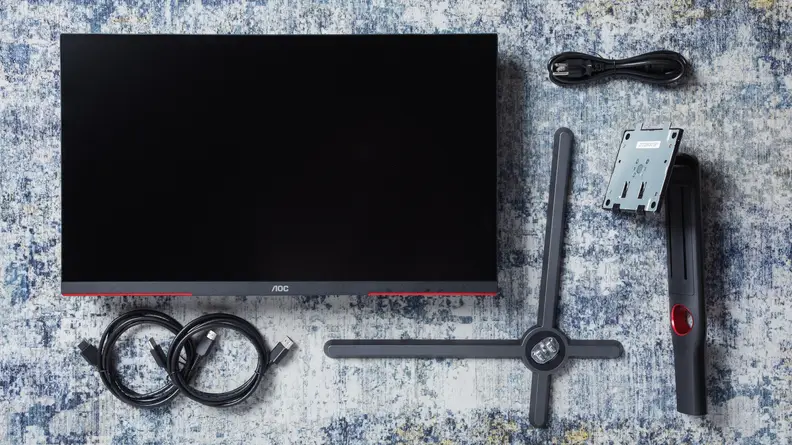 The AOC Q27GX3MN gaming monitor on a rug features accessories.