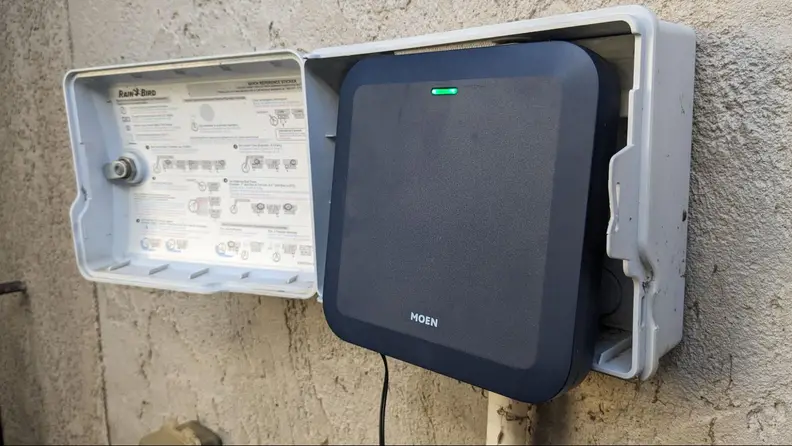 Moen Smart Sprinkler Controller attached to control box on exterior wall.