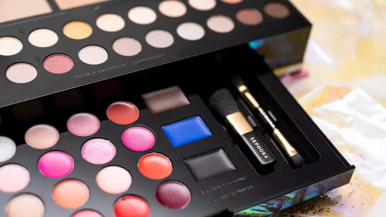 A closeup on the brown, blue, and black eyeliners in a makeup palette.