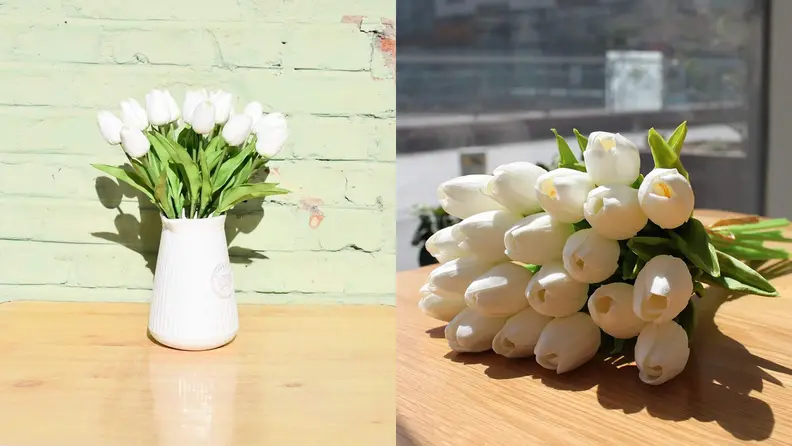 On left, white faux tulips in white vase, in front of green brick wall, on top of desk. On right, white faux tulips laying on top of desk in front of window.