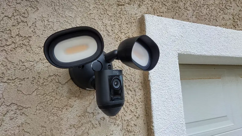 The Ring Floodlight Cam hanging on a home next to a garage door