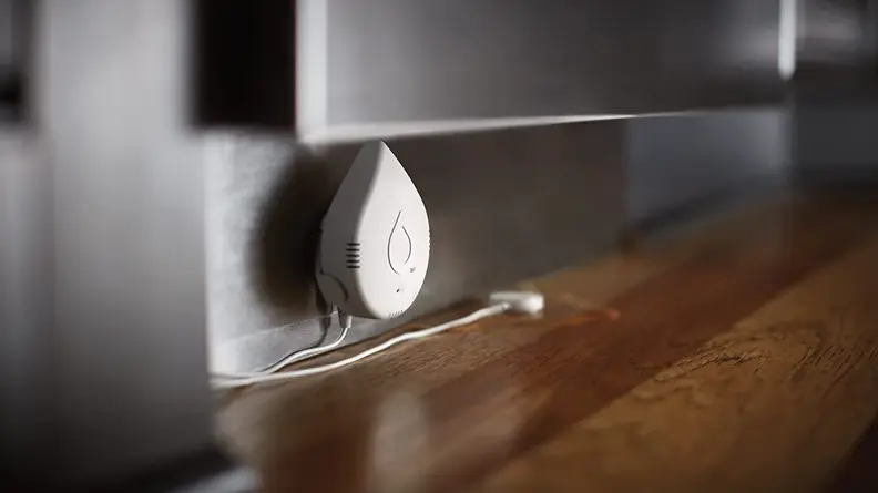 Raindrop shaped plug plugged into wall outlet on ground.