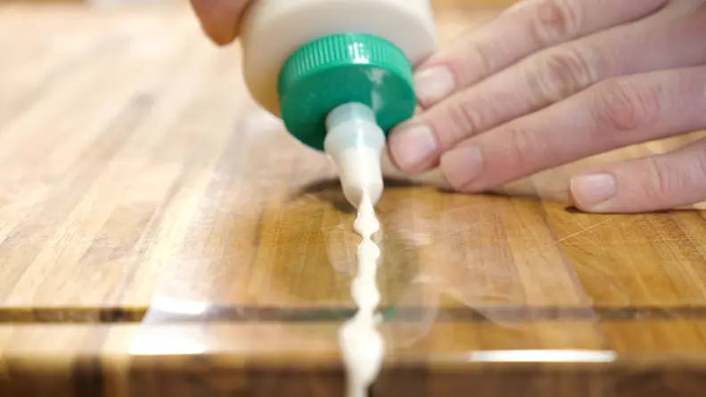 With your cutting board lined with plastic, apply the glue directly to the crack and let it dry.
