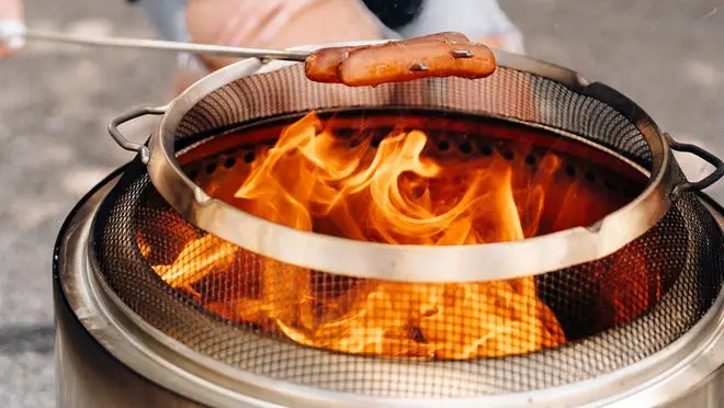hot dog roasting over solo stove fire with shield