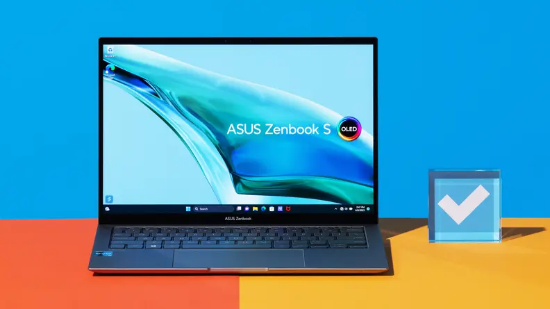 The Asus Zenbook S 13 OLED (2023) on an orange table with a blue background.