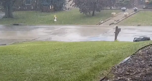 Automower 450XH EPOS robot lawn mower moving across lawn on a heavy rainy day.