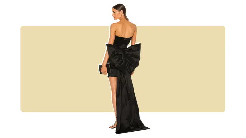 A silky black mini dress with a long, bow-accent train along the back.