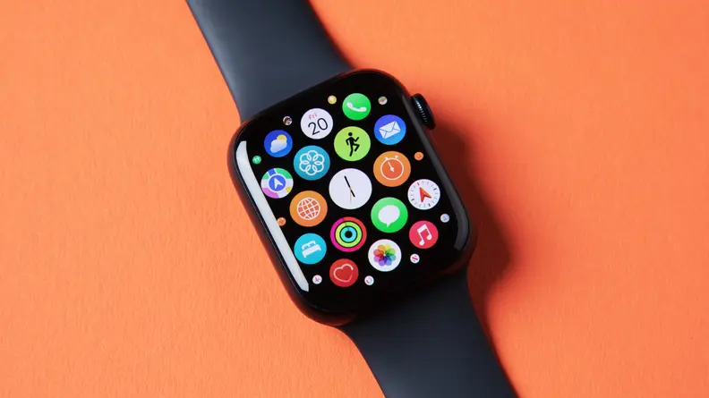 An Apple Watch Series 8 with its app interface open, sits on an orange background.