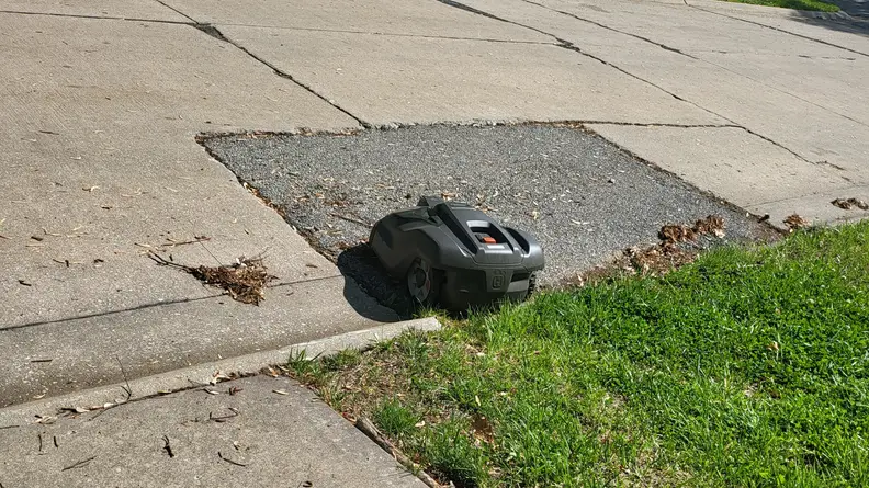 Automower parked in the street just beyond the yard