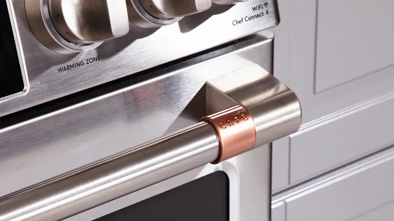 Close-up of a customizable handle detail of the Café CHS900P2MS1 range set in copper.