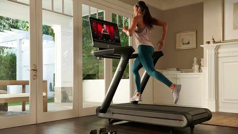 woman in green leggings running on peloton tread
