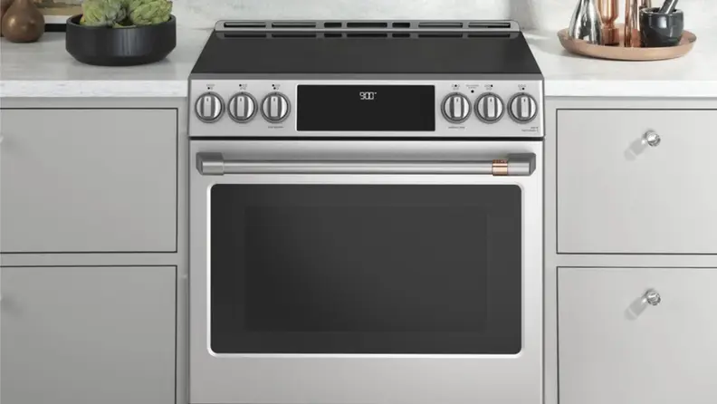 Cafe induction range with rose gold hardware surrounded by kitchen cabinets