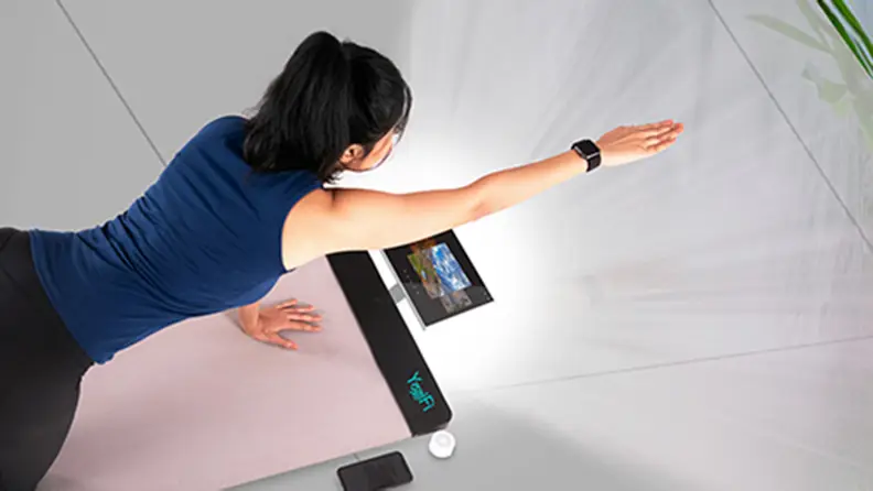 A person practices yoga with the help of the Yogifi smart mat.