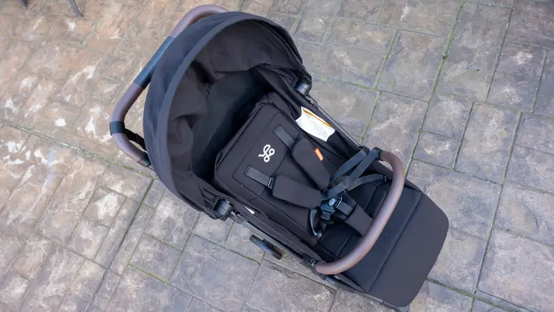 Slight aerial view of black Mamazing stroller, showing the seat and lap bar on a patio.