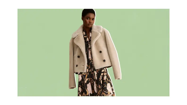 A model wearing a cropped shearling double-breasted jacket with a floral dress.
