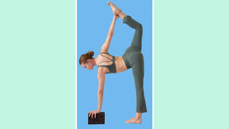 A person performing a yoga pose while holding onto a yoga block.