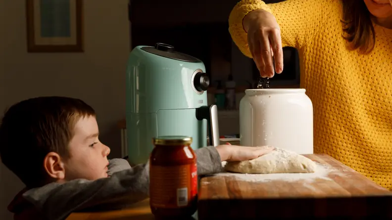 Parent and child making pizza.