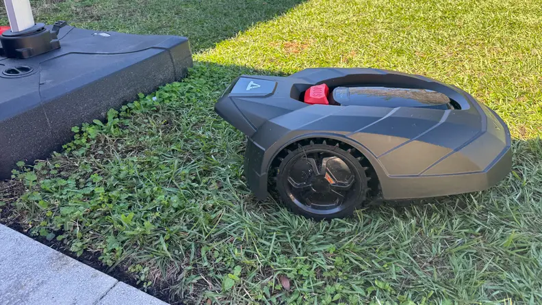 A black Volta robot lawn mower on grass