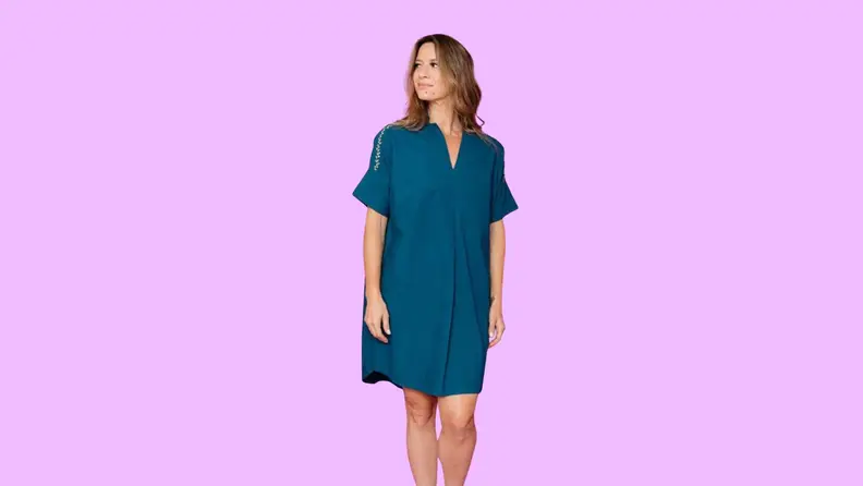 A woman modeling a dress in front of a background.