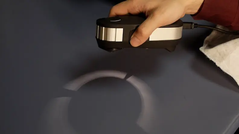 Person using spectroscope on navy fabric swatch to inspect stain.