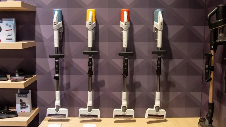 Four Miele Duoflex HX1 stick vacuums shown side by side on display each with different accent colors.