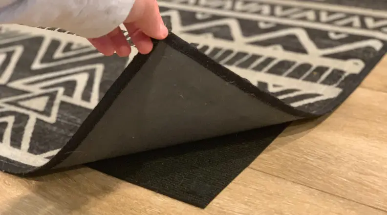 A person lifting up the Ruggable cover to expose the Ruggable rug pad.