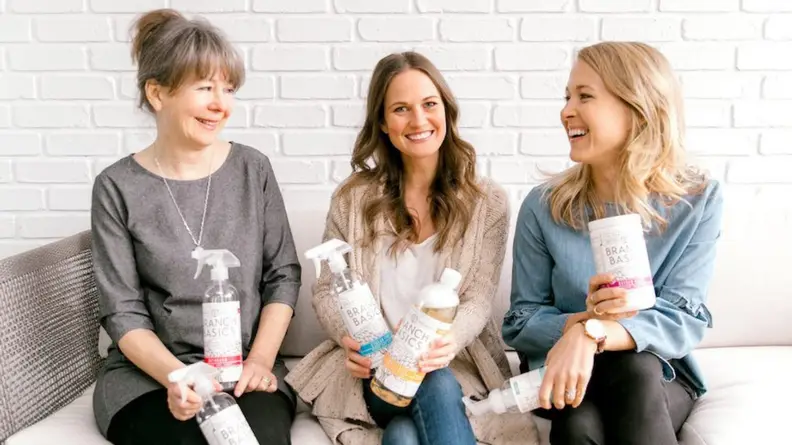 Three of the Branch Basics owners sitting down while holding their products.