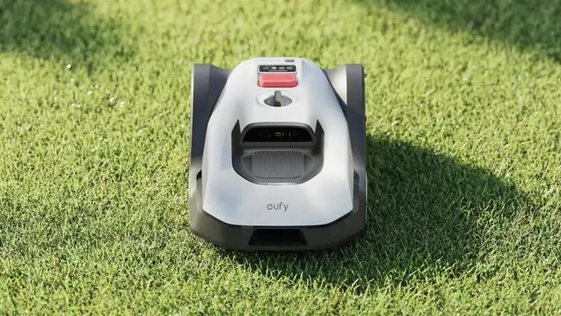 Eufy C15 robot lawn mower sitting on grass in a yard.