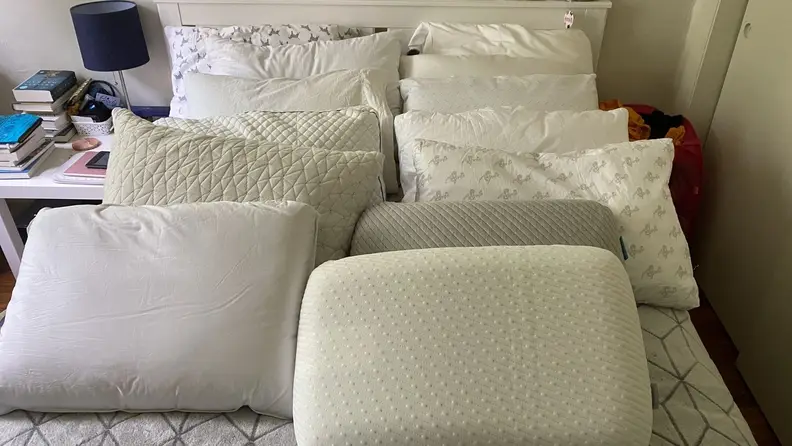a variety of pillows lined up on bed