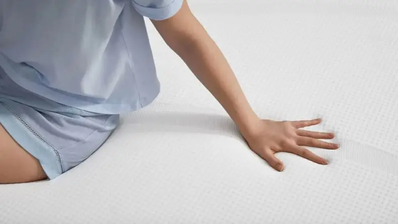 a person sits on the Tempur-Cloud with a hand on it